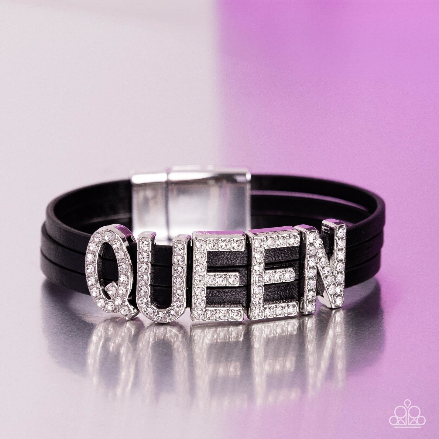 Black leather bracelet with 'QUEEN' letter charms on a purple background.